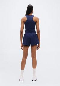 Marineblå tanktop og shorts, tætsiddende design med tekstureret finish, udskåret ryg, elastisk taljebånd og minimal brandingdetalje på toppen.