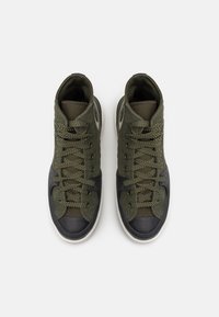 Sneakers typu high-top z oliwkowozielonym zamszem i siateczką, ciemnoniebieską gumową osłoną palców oraz teksturowanymi sznurówkami.