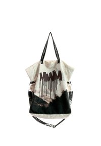 Bolso tote beige con estampado abstracto de montañas en negro, diseño de texto en negro y correa de hombro negra desmontable con letras blancas.