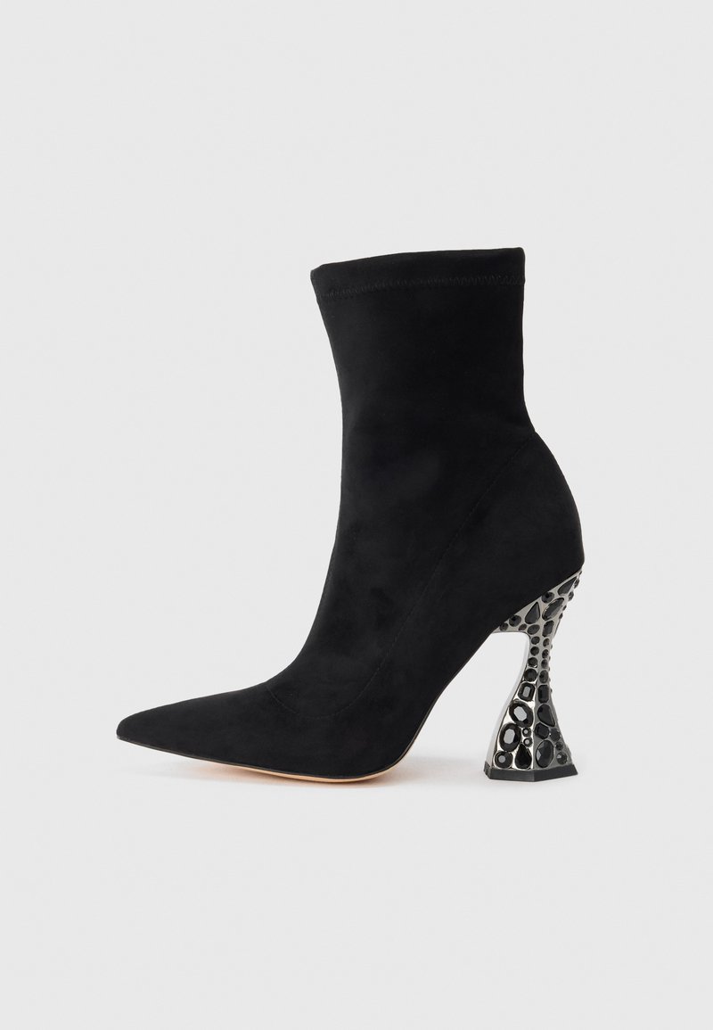 Botine negre din suede până la gleznă, cu vârf ascuțit și toc sculptat cu un model metalic negru. Textură netedă și siluetă ajustată.
