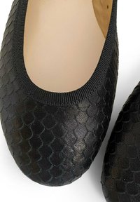 Ballerines noires en simili cuir texturé imitant la peau de reptile. Bout rond, tissu extensible autour du col pour le confort et intérieur lisse.