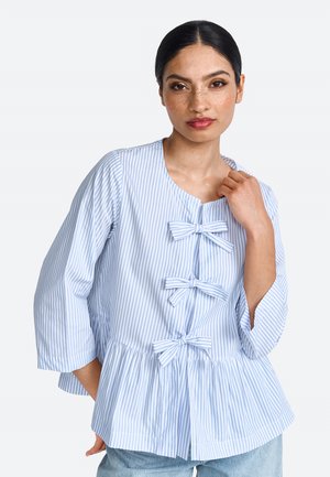 Hellblau-weiß gestreifte Bluse mit Peplum-Design, die drei Schleifchen-Akzente an der Vorderseite und weite Ärmel aufweist.