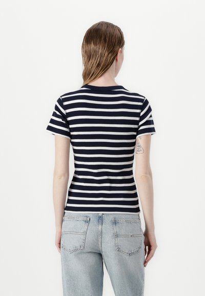 T-shirt à rayures bleu marine et blanches avec des manches courtes, tissu côtelé, col rond, design ajusté et un petit logo sur la taille arrière.