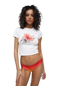 T-shirt bianca corta con stampa di hibiscus rossa, abbinata a slip da bikini con una sfumatura lucida che va dal rosso all'arancione. Tessuto morbido, design aderente.