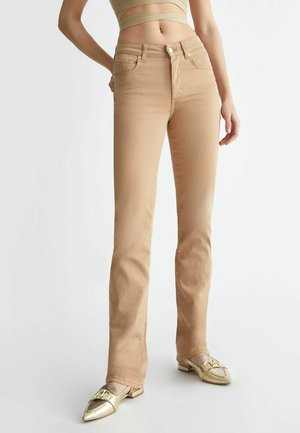 Jeans beige a vita alta con design aderente, dotati di chiusura frontale con bottone, passanti per la cintura e due tasche frontali. Tessuto liscio.