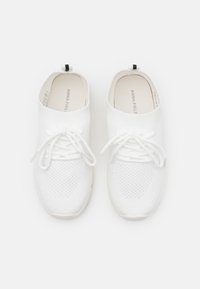 Bíl�é pletené tenisky s prodyšným síťovaným svrškem, kulatou špičkou a zavazováním na tkaničky. Mají měkkou, polstrovanou podešev a černou přezku na snadné nazouvání.