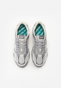 Sneaker grigie chiare con tomaia in rete e materiale sintetico. Presentano lacci, colletto imbottito e sottopiede turchese con il testo "Colmar Originals 1923".