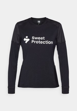 Chemise noire à manches longues avec un col rond et des accents en tissu en maille sur les épaules. Logo blanc "Sweet Protection" affiché en évidence.