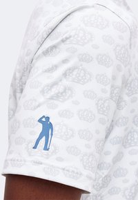 Tissu blanc avec des motifs de couronne gris clair et une petite silhouette bleue d'un golfeur inclinant son chapeau sur la manche.