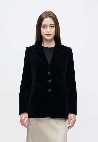Navy blue velvet blazer with a structured design, single-breasted front, notched lapels, and three buttons. Features side pockets and a smooth texture.