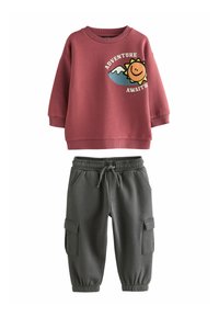 Bordeauxrotes Sweatshirt mit einem grafischen Sonnendesign und dem Text "ABENTEUER ERWARTET"; kombiniert mit grauen Cargo-Hosen mit elastischen Bündchen und Taschen.