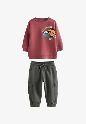 Sweatshirt- og joggersæt. Lyserød sweatshirt med smiley-grafik, ribbede manchetter; grå joggers med elastisk talje og cargo-lommer.