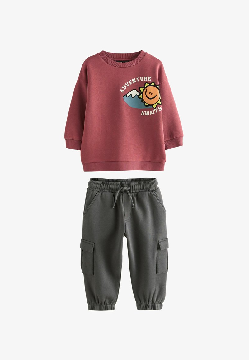 Ensemble sweat-shirt et joggings. Sweat-shirt rose avec un graphique de smiley, poignets côtelés ; joggings gris avec taille élastique et poches cargo.