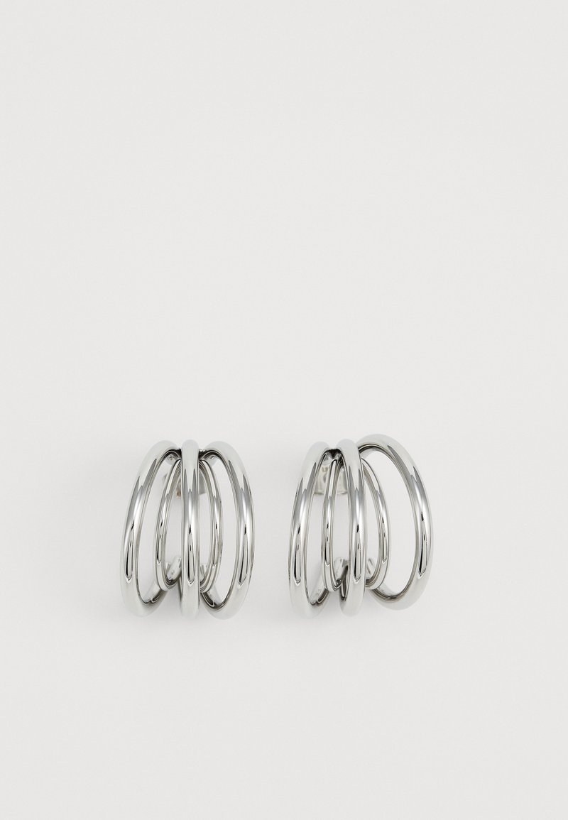 Silver-toned earrings featuring four interlocking circular hoops. Smooth surface with a polished finish, creating a shiny appearance.