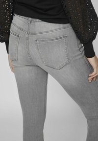 Vaqueros grises ajustados de denim, con un diseño entallado, bolsillos traseros y costuras de contraste a lo largo de las costuras.