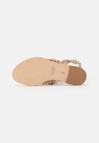 Beige sandaalit, joissa on nauhat ja teksturoitu päällinen koristeellisten helmien kera. Silkkinen pohja, jossa on kapea muoto, merkitty bränditiedoilla.