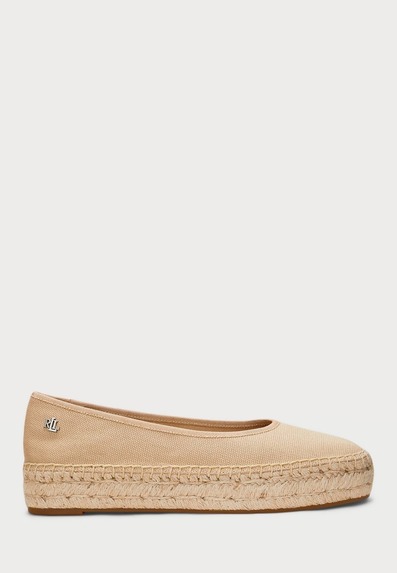 Chaussure plate beige en toile avec semelle plateforme en jute tissée et petit logo métallique de la marque sur le côté.