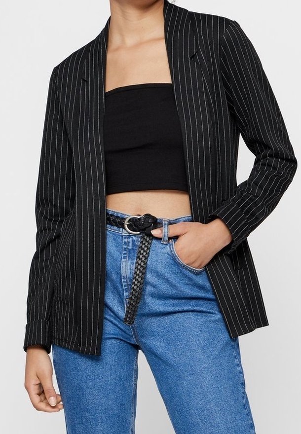 Černý pruhovaný blazer s přizpůsobeným střihem, dvě klopové kapsy, v kombinaci s černým crop topem a modrými džíny s vysokým pasem, doplněné o pletený opasek.