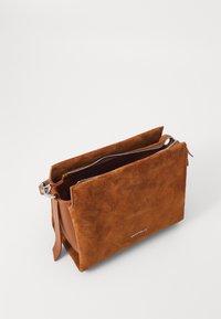 Brun ruskinds pouch taske med lynlås, glatte læderdetaljer og dekorativ syning. Minimalistisk design med en indvendig lomme.