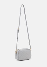 Steppelt szürke crossbody táska téglalap alakú formával, arany cipzár díszítéssel és állítható pánttal. Puha tapintású anyag.