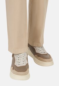 Superge v bež in rjavih tonih, ki se pona�šajo z mešanim materialnim dizajnom z akcenti iz semkega usnja, teksturirano srednjo podlogo in belimi vezalkami.