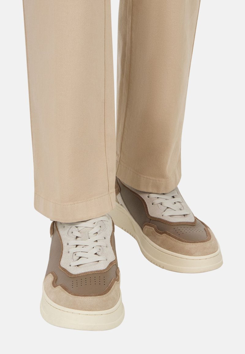 Superge v bež in rjavih tonih, ki se ponašajo z mešanim materialnim dizajnom z akcenti iz semkega usnja, teksturirano srednjo podlogo in belimi vezalkami.