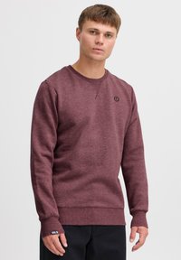 Bordeaux sweatshirt lavet af blødt stof med rund halsudskæring, ribbede manchetter og en lille logo-detalje på brystet. Har en afslappet pasform.