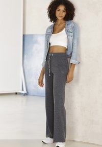 Gray wide-leg sweatpants with a drawstring waist, paired with a white crop top and light blue denim jacket. Smooth texture, minimal branding.