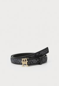 Svart vävt tygbälte med läderdetaljer, prytt med en logobuckle i guldton. Texturen har ett diamantmönster på tyget.