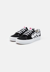 Black suede sneakers with white laces, featuring a patterned black and white checkered design on the side, and a white rubber sole.