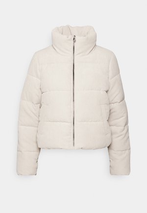 Krótkia kurtka puchowa w jasnobeżowym korduroyu, z wysokim kołnierzem, zamkiem błyskawicznym z przodu oraz dwoma bocznymi kieszeniami z poziomym pikowaniem.