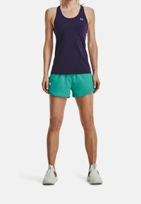 Top deportivo morado con diseño de espalda nadadora, combinado con pantalones cortos turquesa. Ambos hechos de una tela ligera. Zapatillas deportivas blancas.