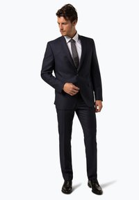 Marineblauer Anzug mit schlanker Passform, glatter Textur und Ein-Knopf-Verschluss. Begleitet von einem weißen Hemd und einer grauen Krawatte.