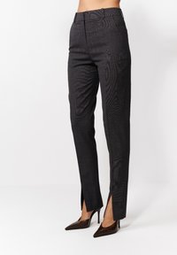 Kohandatud mustad püksid tekstuurse mustriga, kitsas lõige ja küljesplitsid allääres. Viimistletud siledaga ees ja vöökohaga.