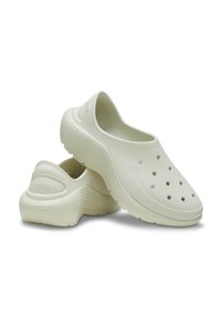 Light beige plastic clogs with a perforated upper for ventilation, a textured sole, and a rounded toe design. Logo embossed on the heel.