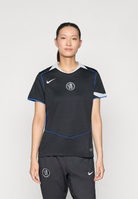 Svart Nike-drakt med grå krage og blå detaljer, med en sirkulær logo i midten. Glatt stoff med korte ermer.