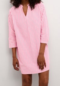 Randig tunika klänning i rosa och vitt med V-ringning, trekvartslånga ärmar, lös passform och mjuk bomullstextur, som når mitten av låret.