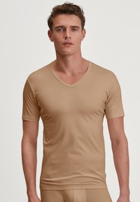 V-hals, kort mouw shirt in een lichtbeige kleur. Gemaakt van soepel, rekbaar materiaal voor comfort en pasvorm. Eenvoudig ontwerp zonder patronen.