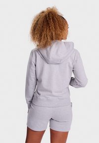 Sivá mikina s kapucňou na šnúrku, vyrobená z mäkkej zmesi bavlny, s klokankou, v kombinácii so zodpovedajúcimi sivými šortkami pre súladný vzhľad.
