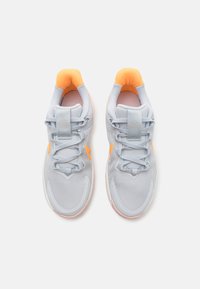 Baskets de sport gris clair avec des accents orange, tige en tissu texturé, col rembourré et design à lacets. Semelle en caoutchouc avec motif de semelle visible.