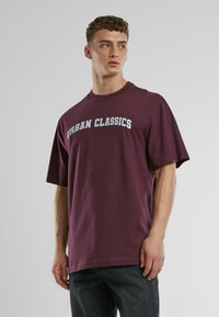 Bordo pārmērīgs t-krekls, izgatavots no kokvilnas, ar uzrakstu "URBAN CLASSICS" kontrastējošā gaiši zilos toņos uz priekšpuses. Īsas piedurknes, apaļais kakls.