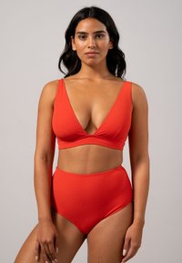 Rood tweedelig badpak met een diepe V-hals top en brede banden, en hoge taille onderkant. Glad textuur, minimale hardware.
