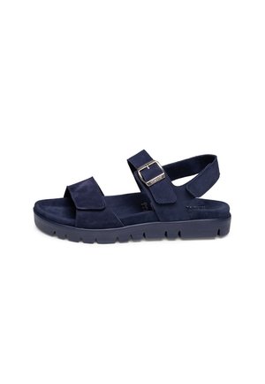 Navy blue flat sandal with thick sole, adjustable buckle strap over the foot, and velcro strap at the heel.