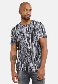 Short-sleeve T-shirt in black and white with a wavy, abstract pattern. Features a round neckline and a regular fit, made from soft fabric.