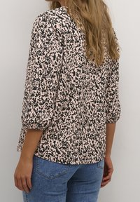 Top rosa chiaro con motivo animalier nero, maniche tre quarti e vestibilità rilassata. Realizzato in un morbido tessuto testurizzato.