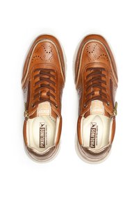 Zapatillas de cuero marrón con detalles perforados, un zipper en el lateral y suelas de goma blanca. Presenta una plantilla con marca. Diseño de ancho extra.