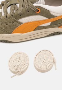 Sneaker con tomaia in suede e rete verde oliva, accenti arancioni e suola intermedia beige. Include due lacci beige arrotolati.
