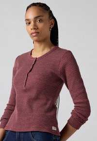 Camicia a maniche lunghe a scacchi rossi e crema con collo tondo e dettagli con bottoni. Realizzata in tessuto testurizzato, presenta un'etichetta con logo all'orlo.