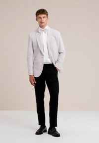 Heledhall sägiviik koos šaaliga, valge ülikonna särgi ja mustade pükstega. Lisatud on lips ja läikivad mustad kingad.