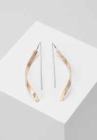 Gold and silver drop earrings with a curved, elongated shape. Glossy finish with a smooth texture and minimalist design.